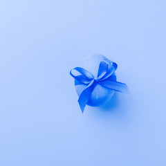 Blue egg with satin bow on blue background. Festive spring concept. Color trend. Selective focus close-up. Minimalism is