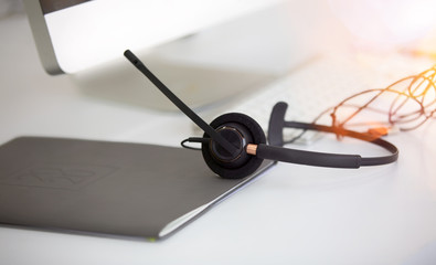 Communication support, call center and customer service help desk. headset on Book and laptop computer keyboard.