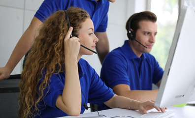 Call center staff in blue T-shirt accompanied by her team. Smiling customer staff support operator...
