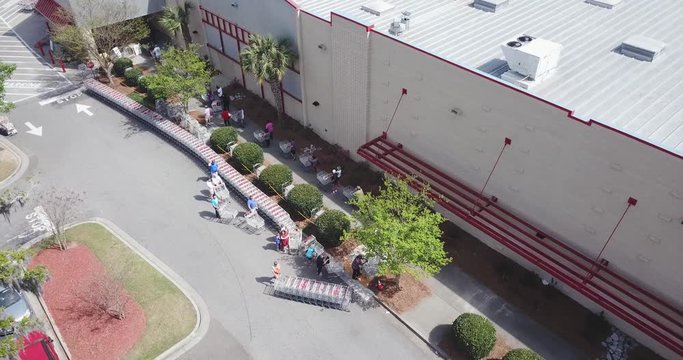 Shop employee adding more carts to a huge line while line of people waiting outside because of gathering restrictions inside the shop. North Charleston, South Carolina, USA