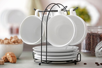 Holder with cups and saucers on kitchen table