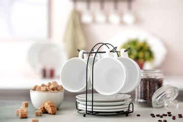Holder with cups and saucers on kitchen table