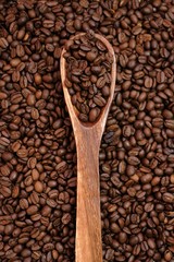 Coffee beans in a wooden spoon on coffee beans background.Roasted coffee beans close-up.