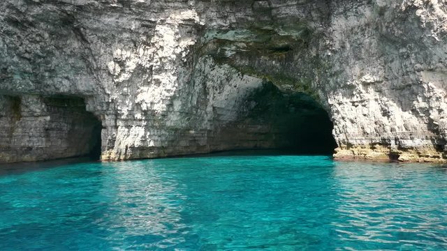 Tracking shot entering a cave inside a blue turquoise sea water