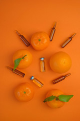 Vitamin C concept. Tangerines  fruits, vitamin C in glass ampoules on a bright orange...