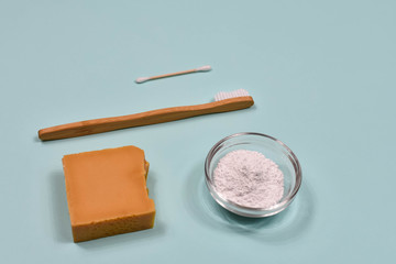 Zero waste concept. Toothbrush, tooth powder and soap on a blue background. Eco-friendly bamboo toothbrush.