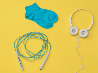 Jump rope, headphones and sports socks on a yellow background. The color trend. Flat lay.