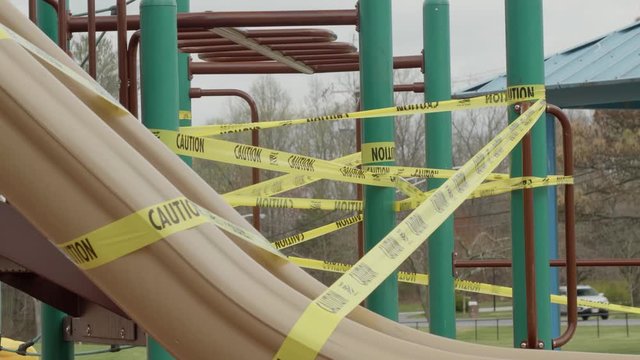 Close-up shot of a lonely playground with caution tape due to social distancing and the COVID-19 coronavirus outbreak. 4K UHD, V-Log corrected. Shot on a Panasonic GH5.