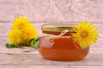 Dandelion jam in jar  isolated on old wooden background. Sweet and healthy food. 