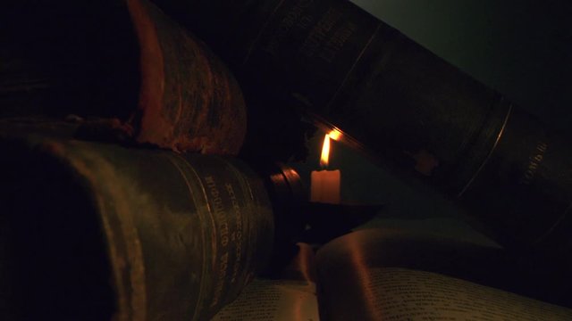 Antique Books Illuminated By A Candle Studio Shot Enlightenment History Stack slow motion 8K