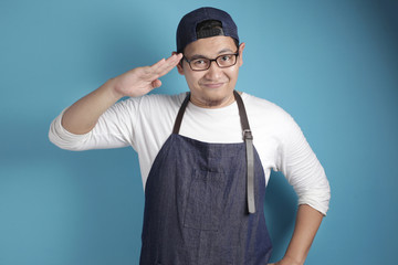 Portrait of happy smiling Asian chef or waiter doing salute gesture, ready to serve