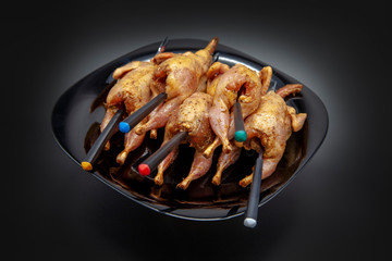 Fresh quail carcasses before cooking on a black background