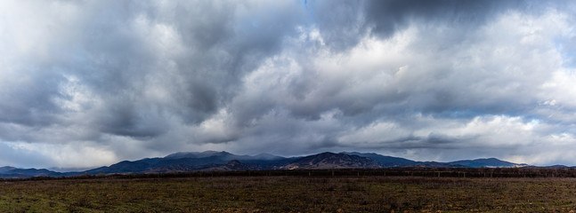 View to mountain and field with dramatic cloudy sky