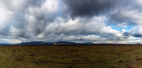 View to mountain and field with dramatic cloudy sky