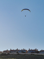 Paraglider flying in blue sky.