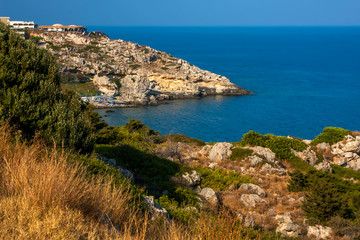 Cove near rocky shores with grass under a blue sky