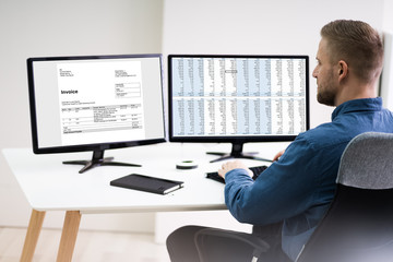 Businessman Looking At Invoice On Computer
