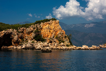 Fototapeta na wymiar Rock in the sea, coast, mountains and sky with clouds