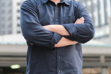 Confident male business executive  with arms crossed standing in front of office building