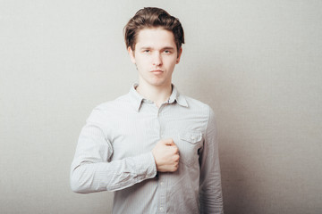 Young handsome man is swearing allegiance with his hand, fist on chest. Closeup portrait arrogant,...