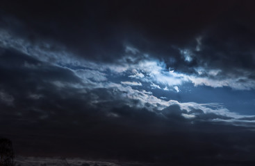 Fototapeta na wymiar Mond hinter Wolken, diagonal aufgerissen, leuchtend, bläulich, kalt
