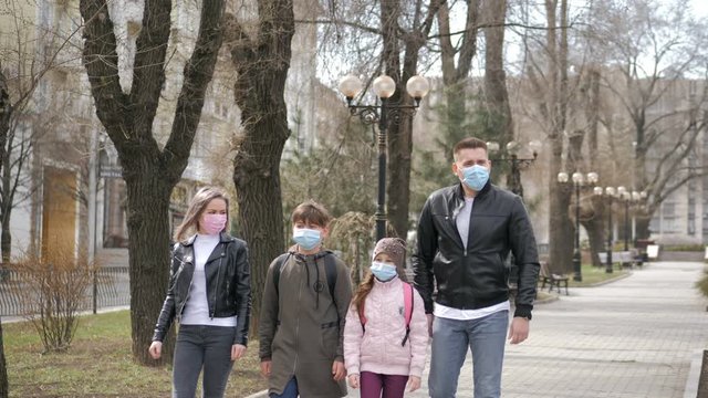 A family walks in a park wearing masks protecting from influenza virus or coronavirus