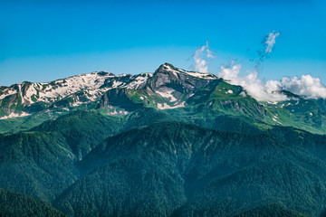 High mountains with green slopes and snowy peaks.