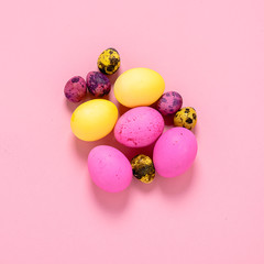 Happy easter concept. Colored eggs on a pink background. Square frame flat layout.