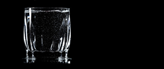 A glass of water is isolated on a black .