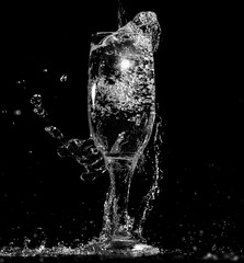 Splashes and drops of water in a glass are isolated on a black .