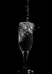 Splashes and drops of water in a glass are isolated on a black .