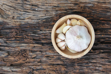 fresh garlic in wooden bowl on wooden background. Concept with vitamin and energy food for saving from COVID-19 virus.
