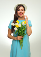 Happy woman in blue dress and summer hat holding tulip flowers bouquet.