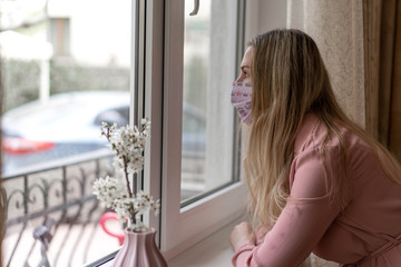 Girl in a pink dress and a pink medical mask. Self-isolation at home.