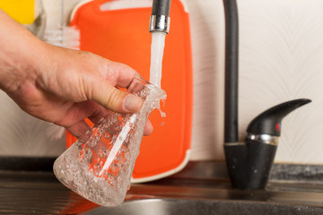 A man pours tap water into a glass flask.