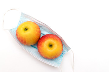 Two apples are lying on a protective medical mask on a white background.Agricultural crisis linked to the coronavirus pandemic 2020.Harvest coronavirus concept. China fruits.