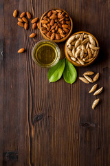 Almond oil - for cooking - in glass bowl near nuts on wooden background top-down copy space