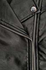 Fragments of a black artificial leather jacket with rivets and zippers. Background for clothes and...
