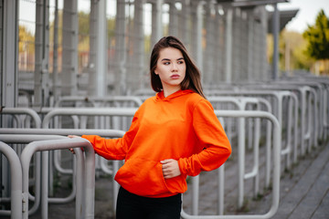 Fototapeta premium Close-up portrait of blissful woman in trendy round sunglasses posing in new orange sweater. Indoor photo of amazing white girl in warm cardigan having fun at home.