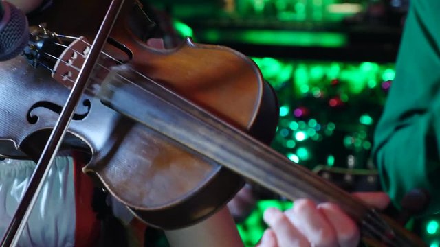 Symphonic orchestral sound conception. Close-up shot of girl violinist enthusiastically playing the violin indoors on dark background. stringed instruments at work, Full hd