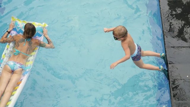 Little boy swims with mom in the pool on vacation in Asia, baby swimming. Mom and son swim in the pool on the mattress.