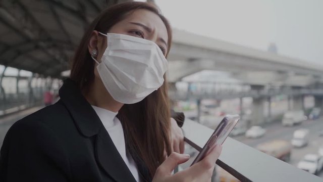 Business woman using a smartphone to follow the news City during the crisis of the Covid-19 virus and must take care of themselves from the virus infection.

