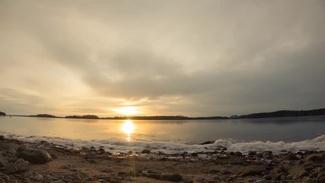 Thin ice layer moving at freezing shore during sunset. Time lapse shot.