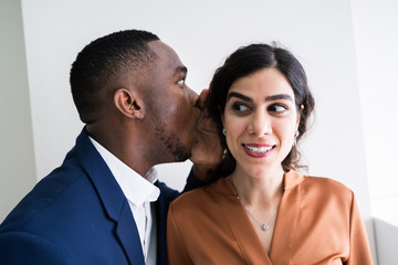 Businessman Whispering Into Female Partner's Ear