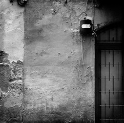 Detail of exterior of building in square format, with section of window grill and electrical box,edited for intentional grunge black and white tin type look