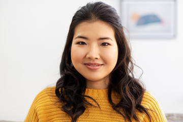 people, ethnicity and race concept - portrait of happy smiling asian young woman at home