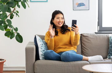 people, technology and communication concept - happy smiling asian young woman in yellow sweater...