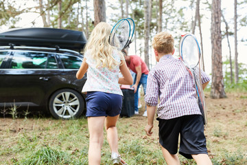Kinder mit Badminton Schlägern laufen zum Auto