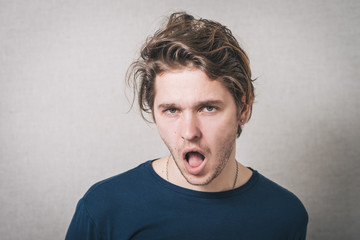 Puzzled handsome young man looks at the camera with an uncertain perturbed expression