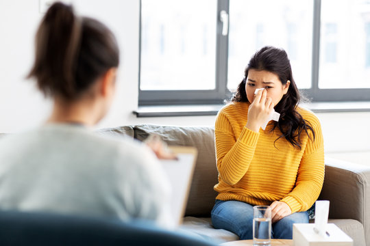 psychology and mental therapy concept - young asian woman patient crying at psychotherapy session